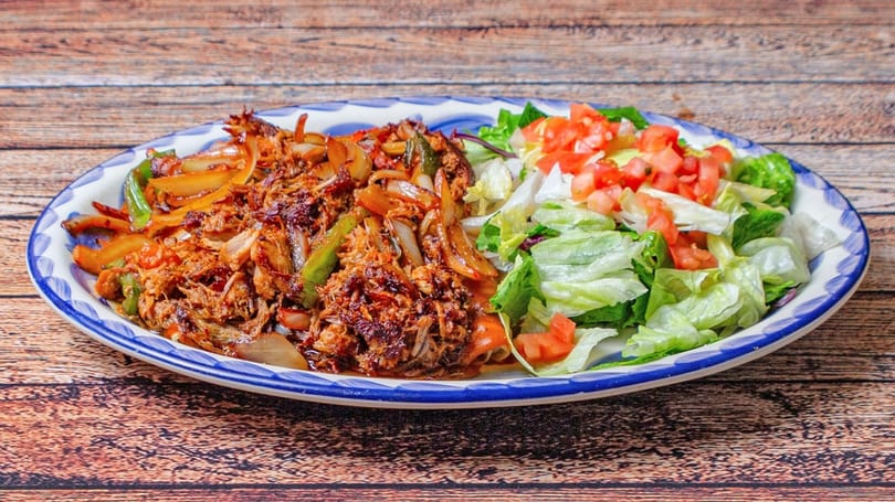 Shredded beef fajitas with sautéed onions and peppers, alongside a fresh green salad with diced tomatoes.